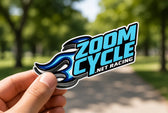 Hand holding a custom blue racing logo vinyl sticker outdoors