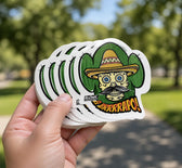 Hand holding a stack of custom green die cut stickers outdoors
